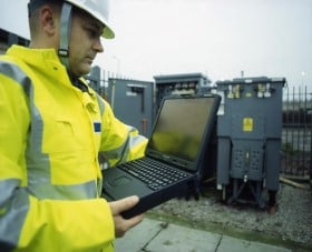 Engineer working on laptop and looking at equipment