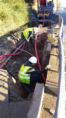 Two engineer laying down underground cable