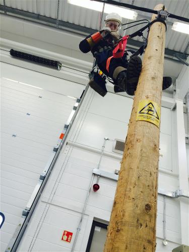 Apprentice climbing up an overhead power line